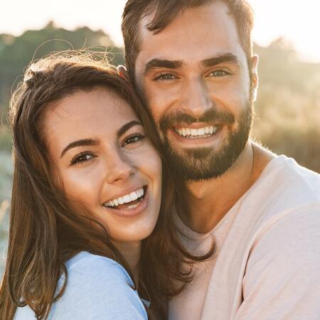 Hübsches junges lächelndes Paar am Strand